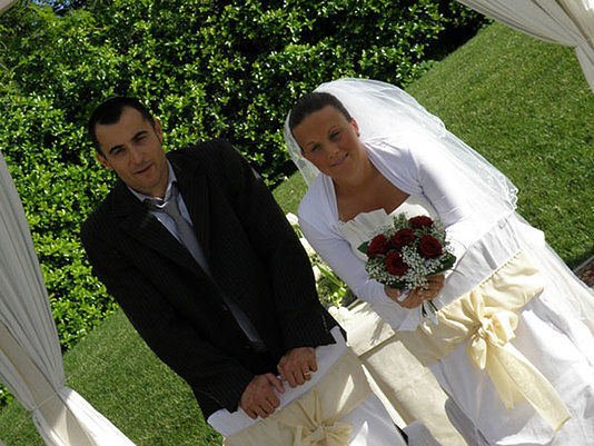 sposi si sotto il gazebo con il bouquet floreale